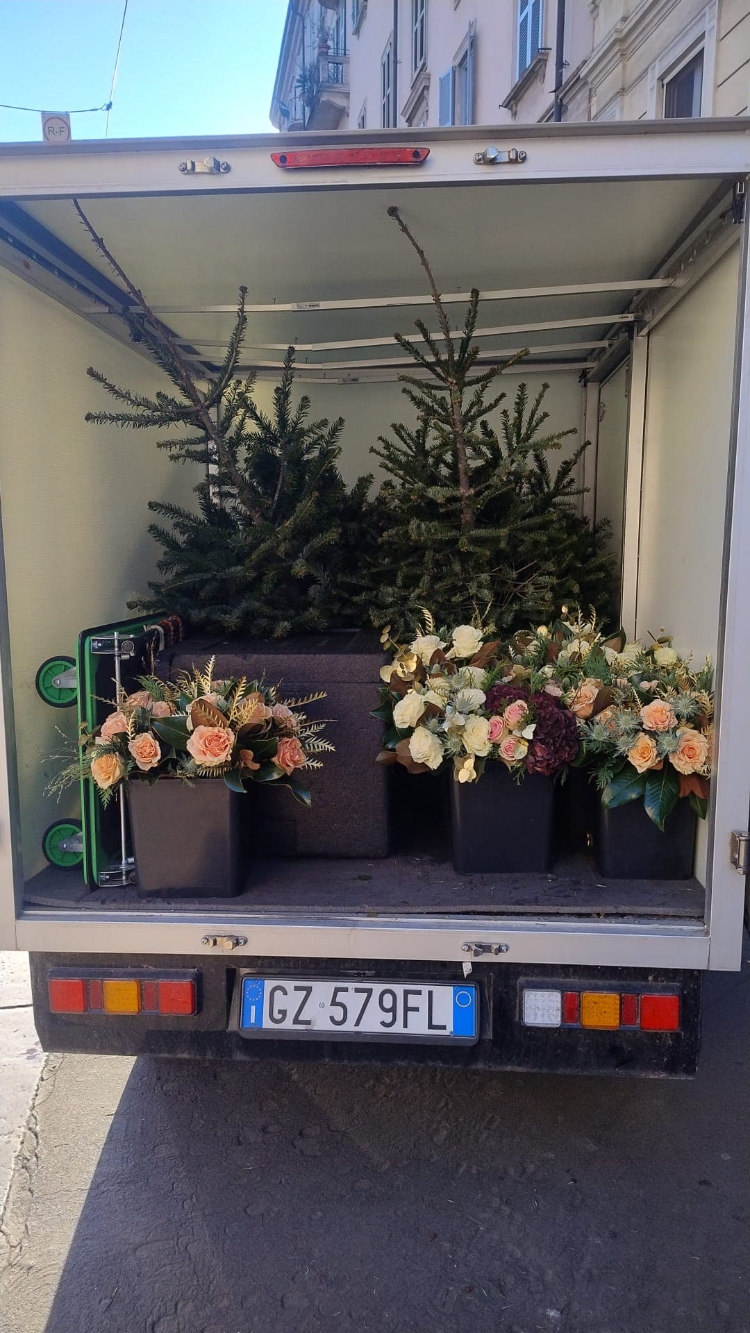 Furgone caricato con composizioni floreali e alberi